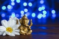 Golden lord ganesha sculpture in daisy flowers over blue illuminated background. Copy space for text Royalty Free Stock Photo