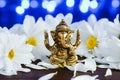 Golden lord ganesha sculpture in daisy flowers over blue illuminated background. Celebrate lord ganesha festival Royalty Free Stock Photo