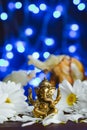 Golden lord ganesha sculpture in daisy flowers over blue illuminated background with defocused elephants Royalty Free Stock Photo