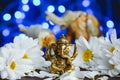 Golden lord Ganesha sculpture in daisy flowers over blue illuminated background with defocused elephants Royalty Free Stock Photo