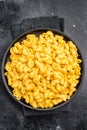 Golden mac and cheese in a black skillet, rustic dark background, fork beside Royalty Free Stock Photo