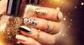 Golden manicure with gems and sparkles. Bottle of nailpolish, trendy accessories Royalty Free Stock Photo