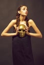 Golden mask in hand of mysterious beautiful woman, glamour