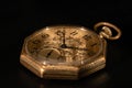Golden mechanical antique pocket watch lying on black surface. Retro pocketwatch with second, minute and hour hand. Old