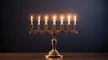 Golden menorah with seven gold candles lighting on dark background.