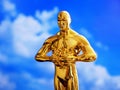 Hollywood Golden Oscar Academy award statue on blue sky background with copy space. Success and victory concept. Royalty Free Stock Photo