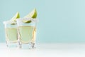 Golden mexican alcohol drink tequila with slice lime, salt on edge in shot drink on green color background, white wood board.