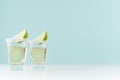 Golden mexican tequila shot drinks with salty rim, piece lime in elegant glass on pastel green wall, white wood table, copy space.