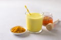 Golden milk with turmeric in a glass with honey on a gray stone Royalty Free Stock Photo