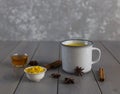 Golden milk, turmeric, honey, ginger root, cinnamon and other ingredients on grey wooden background. Royalty Free Stock Photo