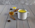 Golden milk, turmeric, honey, ginger root, cinnamon and other ingredients on grey wooden background. Royalty Free Stock Photo