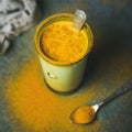 Golden milk with turmeric powder in glass, square crop