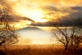 Golden misty November morning. Autumn dawn on a meadow in the fog and silhouettes of mountains