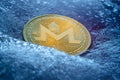 Golden Monero coin, online digital currency frozen in the blue ice. Concept of block chain, crypto market crash. Frozen crypto
