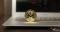 Golden monero stand on silver laptop