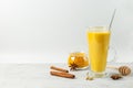 Golden moon milk with turmeric in a tall glass on a light background, spiced latte. Close-up with space