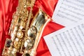 Golden musical instrument alto saxophone on red fabric with music sheets Royalty Free Stock Photo