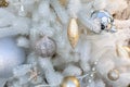 Golden New Year decorations toys on a white plastic Christmas tree. Icicle star ball hanging on branches of eco-friendly fir, Royalty Free Stock Photo