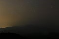 Golden night sky with stars above layer of silhouettes mountain.