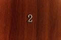 Golden number two sign on brown door of apartments. Closeup Royalty Free Stock Photo