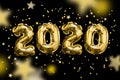 Golden Numbers 2020 made from foil balloons on black space shining stars. Christmas and new year concept Royalty Free Stock Photo