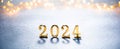 2024 golden numbers on snow with bokeh lights on background. Happy new year 2024