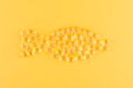 Golden omega capsules like fish on yellow background, flat lay