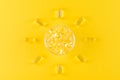 Golden omega capsules like sun on yellow background, flat lay