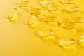 Golden omega capsules on yellow background closeup