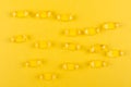 Golden omega capsules on yellow background closeup