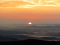 Golden and orange sunrise iluminating a forest. Montains, forests, hills are showed in lays in the picture