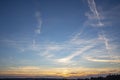 Golden orange sunset and deep blue sky with white feathery clouds contrasting