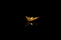 Golden origami boat on black background