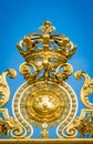 Golden ornate gate crown of Chateau de Versailles on blue sky background. Paris, France,