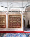 Golden ornate perforated partition framed in white marble arch and ornate carpet