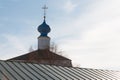 A golden orthodox cross on top of a blue dome on top of the stone white church with a green roof against a blue clear sky Royalty Free Stock Photo