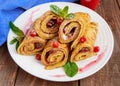 Golden pancakes in the form of roll with strawberry jam and powdered sugar Royalty Free Stock Photo