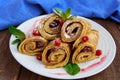 Golden pancakes in the form of roll with strawberry jam and powdered sugar on a white plate on a wooden table Royalty Free Stock Photo