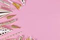 Golden party objects like hats, confetti and gifts on side of pink background Royalty Free Stock Photo