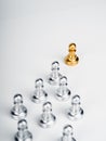 The golden pawn chess piece, leading in front of the group of silver pawn chess pieces.