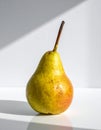 Golden Pear with Brown Stem on a White Surface Under Bright Light Still Life Royalty Free Stock Photo