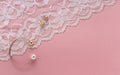 Golden with pearl bracelet and golden earrings on floral white textile on pink background with copy space Royalty Free Stock Photo