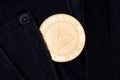 A golden physical TRON coin sticks out of the pocket of black jeans close-up.