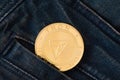 A golden physical TRON coin sticks out of the pocket of blue jeans close-up.