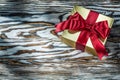 Golden present box with red bow on wooden board Royalty Free Stock Photo