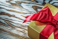 Golden present box with red ribbon on wooden board Royalty Free Stock Photo