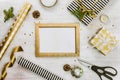 Golden ptoto frame, gift boxes, pine cones and christmas toys and wrapping materials on a white wood old background. Christmas con Royalty Free Stock Photo