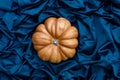 Golden pumpkin on blue silk background for fashion decorative design. Harvest and thanksgiving. Still life minimalism Royalty Free Stock Photo