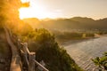 Golden rays of sun on the mountain horizon atop an old path along the edge of the ocean with small waves rolling in toward the As Royalty Free Stock Photo