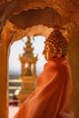 Golden recess with elegant gold Buddha statue draped with the orange buddhist robe Royalty Free Stock Photo